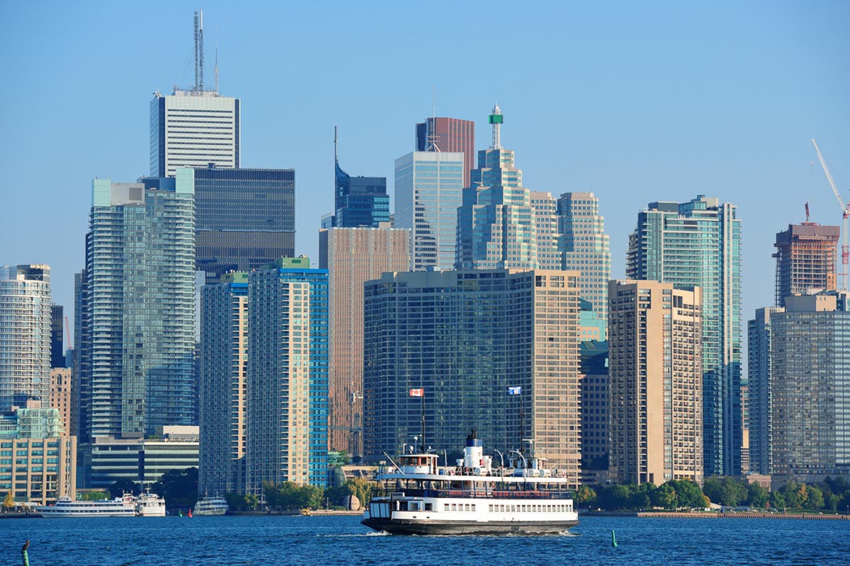 Toronto skyline in the day over lake with urban architecture and ferry.