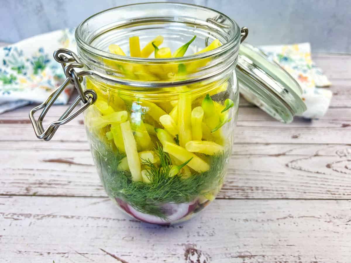 Pickled yellow beans in a jar on a wooden table.