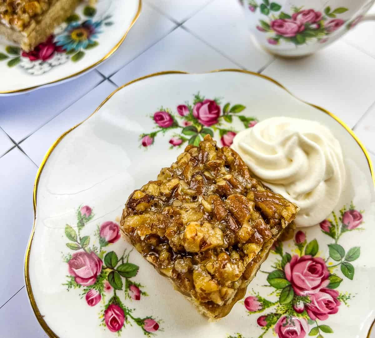 A plate with a slice of pecan cake and a cup of coffee.