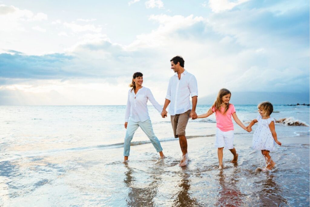 Family walking on a beach at sunset.