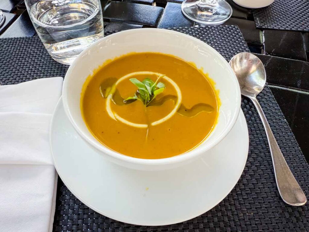 A soup with a leaf at the center of a white bowl.
