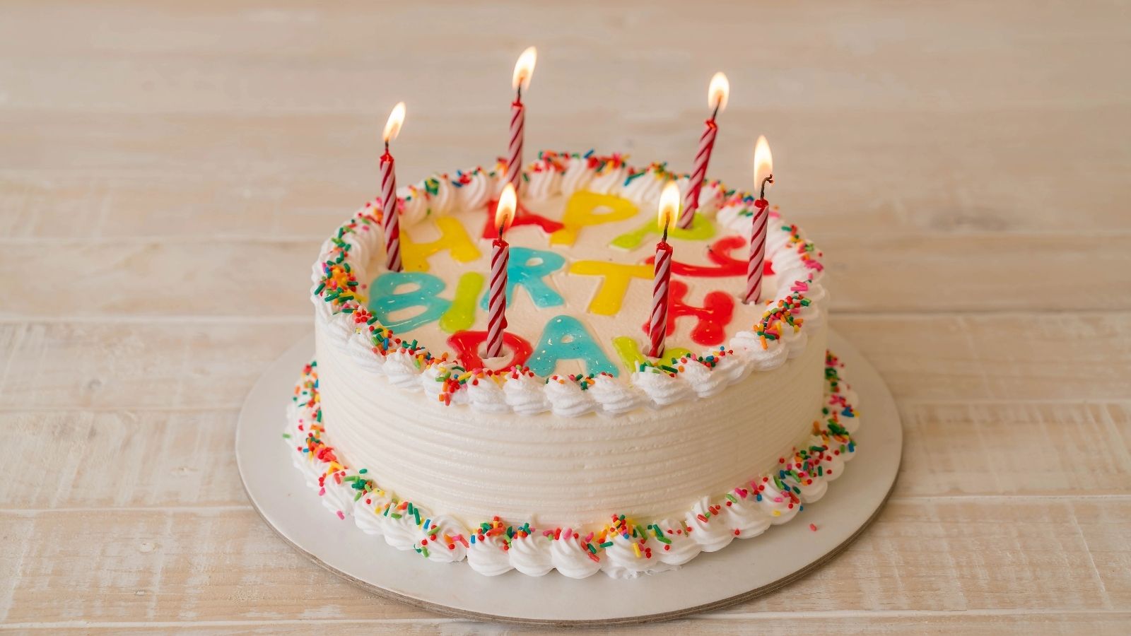 Birthday cake topped with lit candles, displayed on a table.